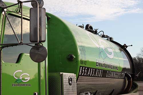 An EnviroServe Company's professional in white gear next to a big tank, showcasing our trusted service
